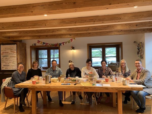 Das gesamte Team am großen Tisch in der Wohnküche.