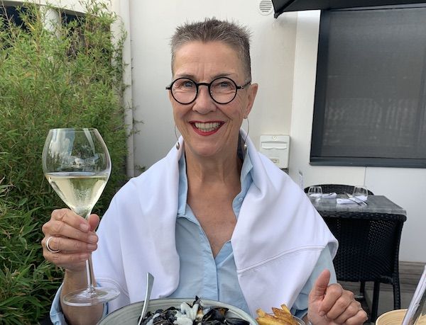 Profilbild von Elke Schulz, Kommunikationskochschule. Sie prostet mit einem Glas Weißwein in die Kamera.